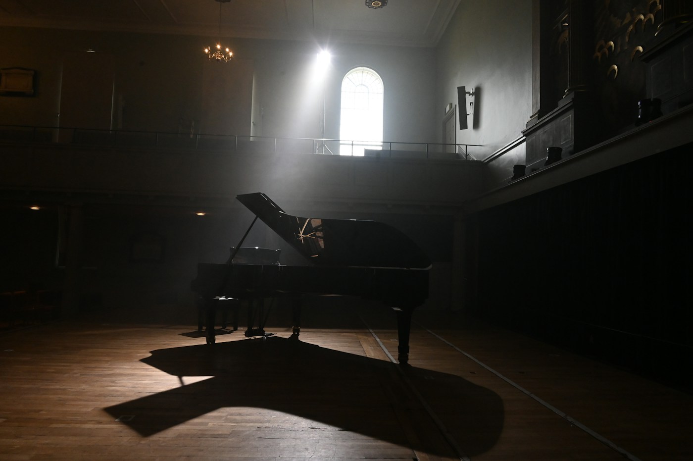 Black grand piano on a wooden floor in the gallery