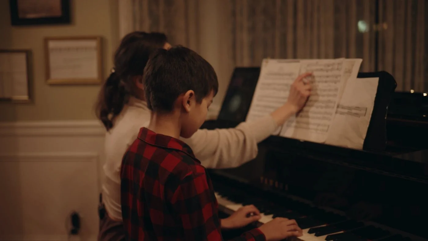A teacher turning the page of sheet music as a young student plays