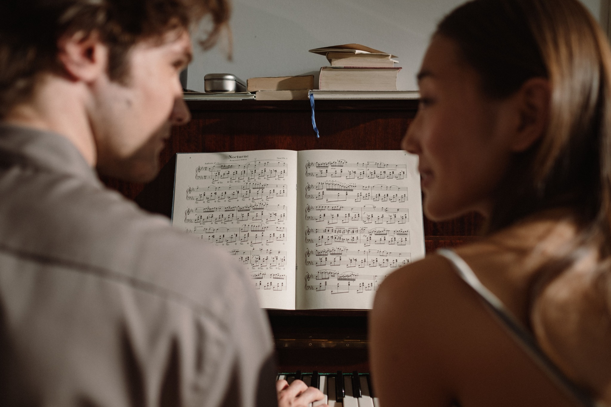 Two people sharing music at a piano
