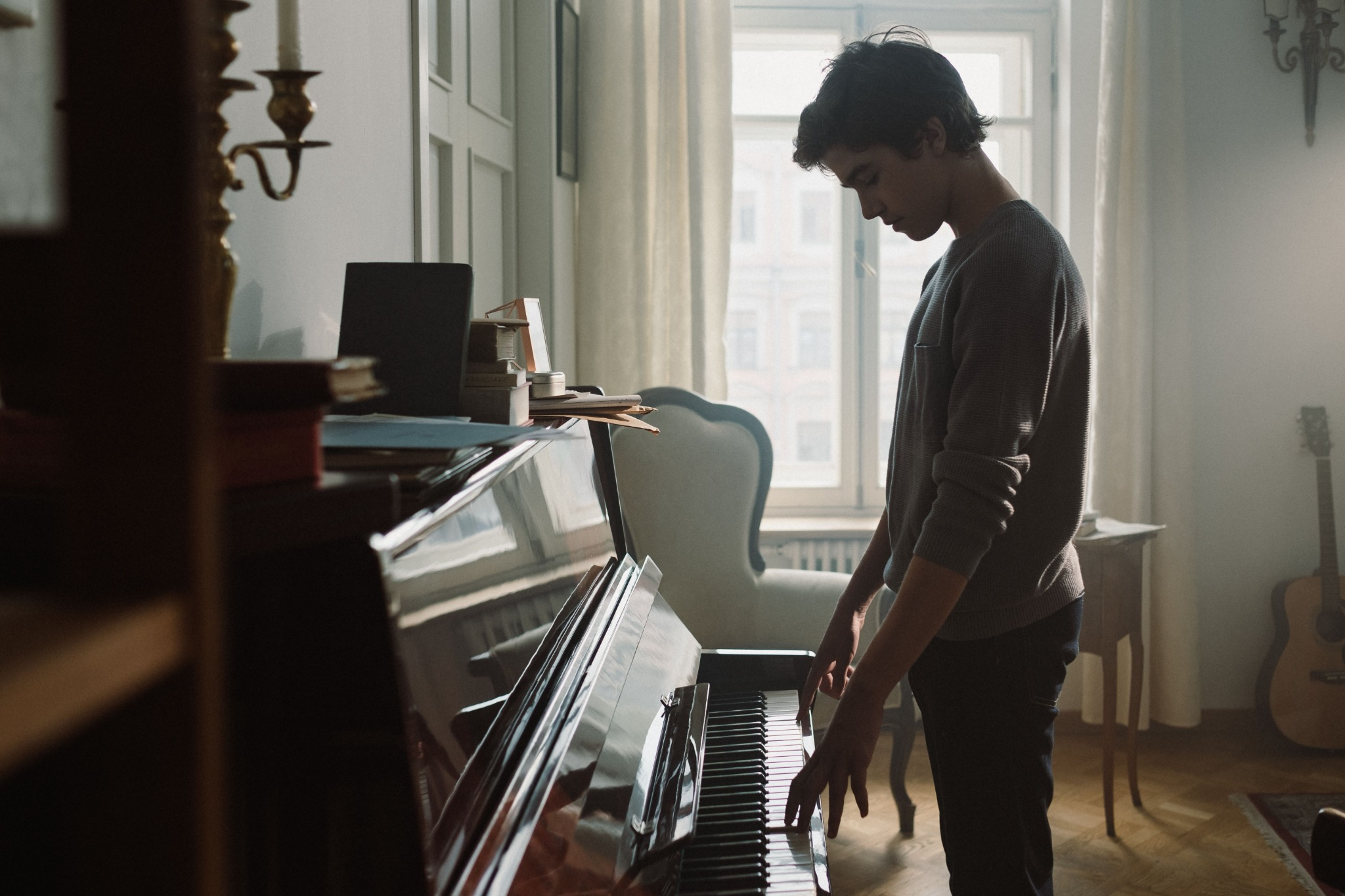 Young musician playing a piano near a window